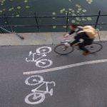 Man riding bicycle alongside the canal next to riddarholmen church in stockholm, sweden